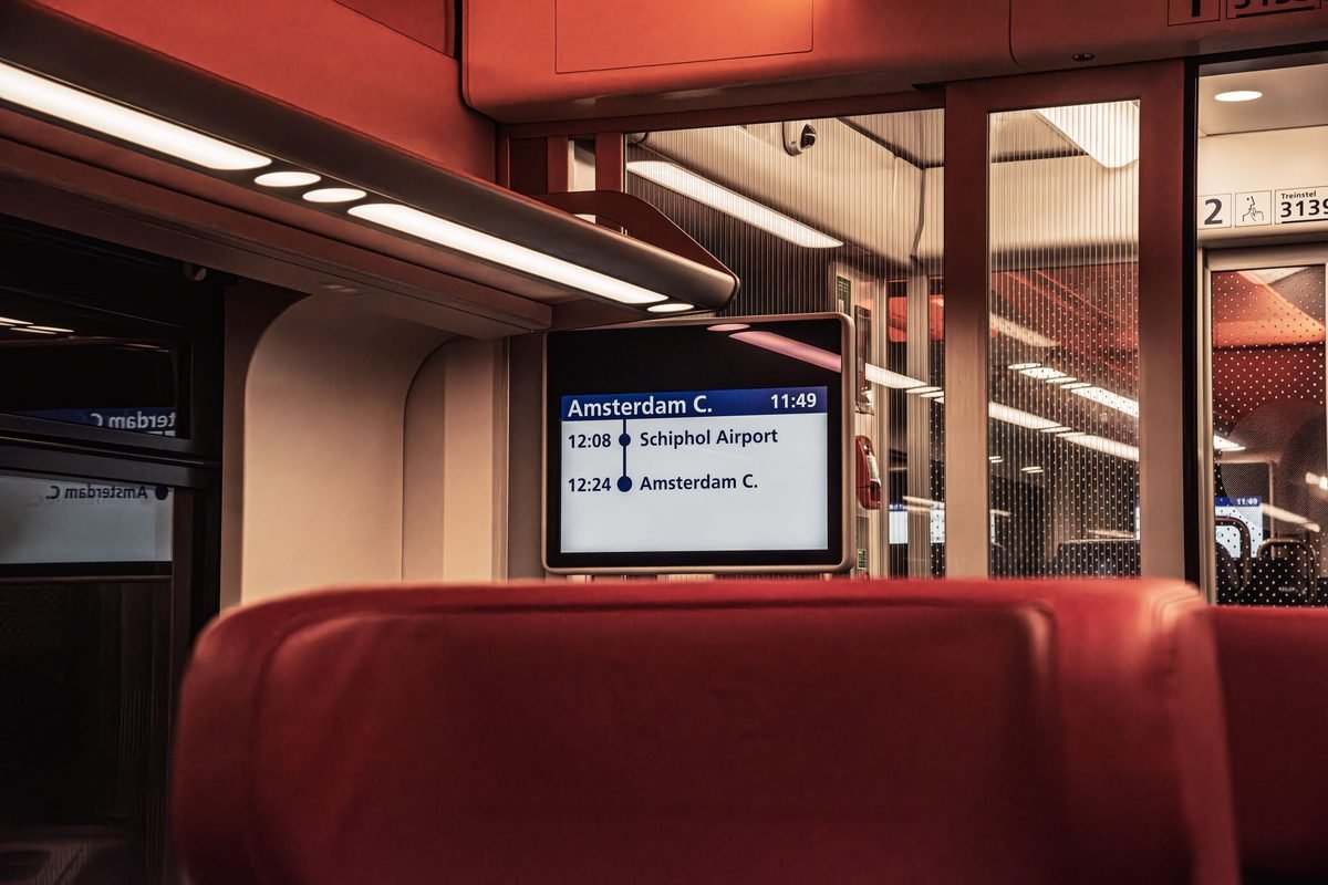 Interior view of a train with a digital screen showing departure info.
