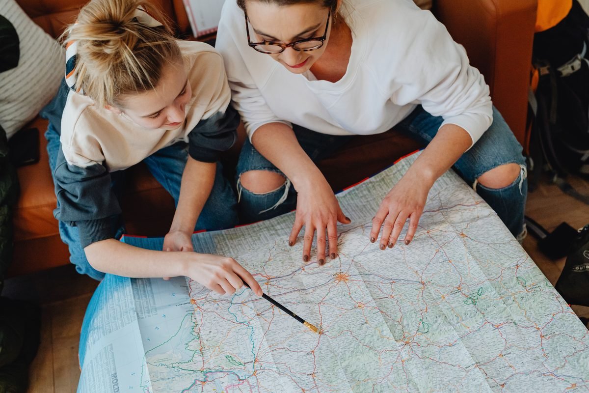 A mother and daughter planning their journey using a large map together.