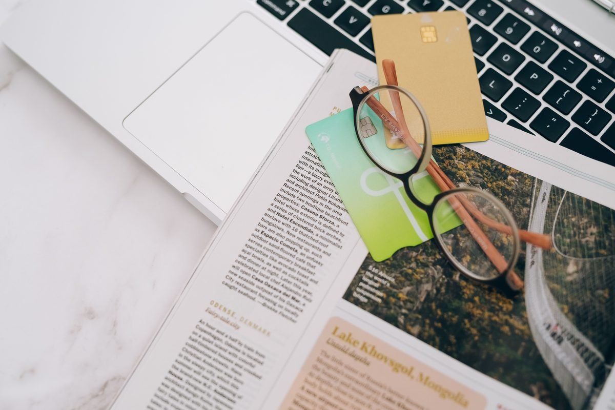 Eyeglasses and credit cards on a magazine and laptop