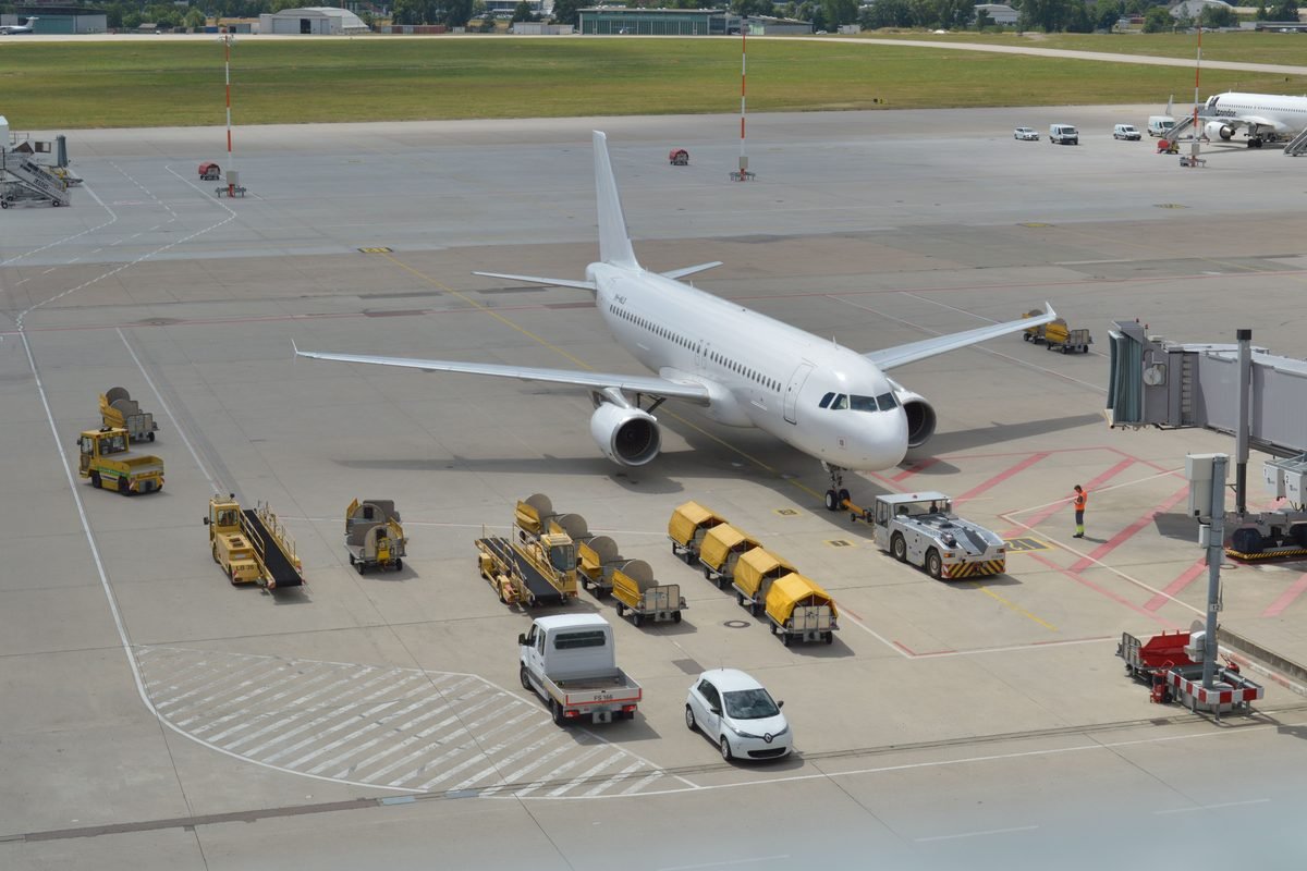 Commercial airplane on airport tarmac with ground support vehicles