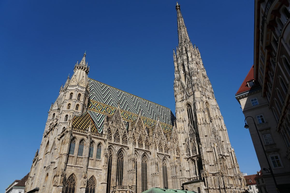 St. Stephen's Cathedral with its patterned tile roof under a bright blue sky.