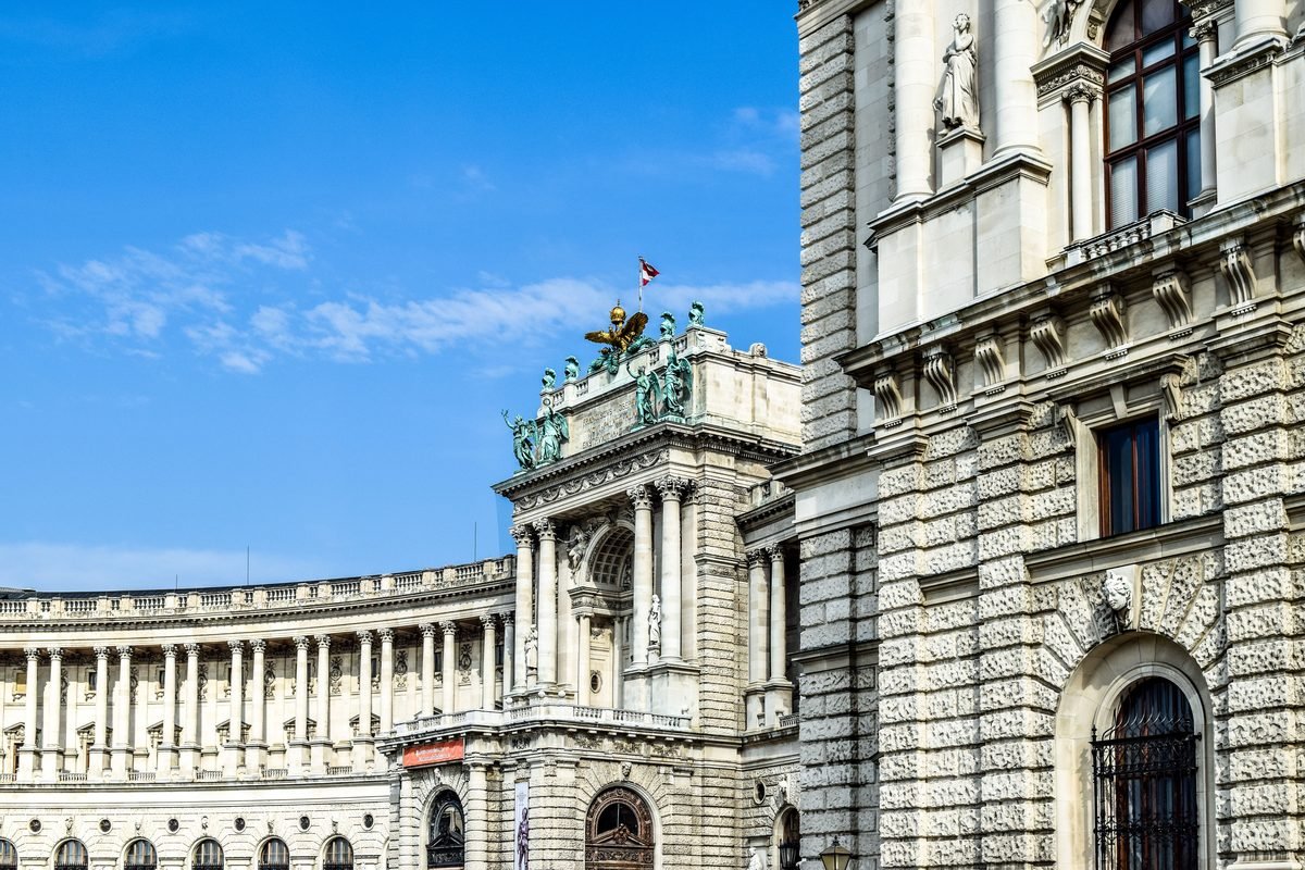 Exterior architectural detail of the historic Hofburg Palace against a blue sky.