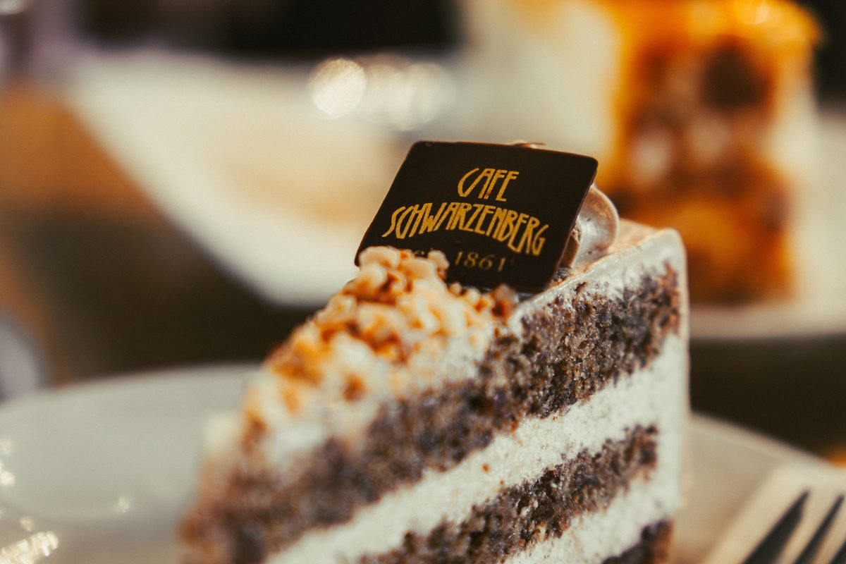 Close-up of a layered cake slice topped with a branded chocolate plaque.
