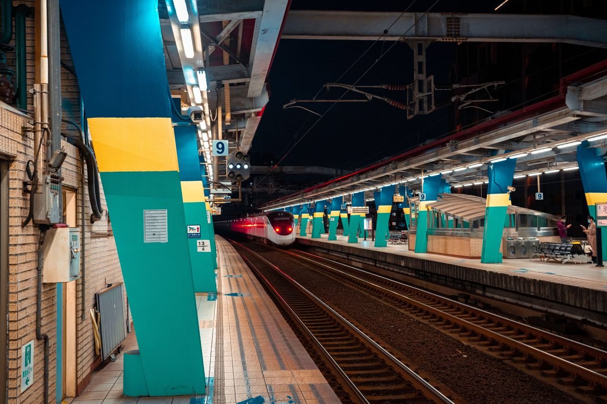 Sleek train arriving at a modern illuminated station platform at night.