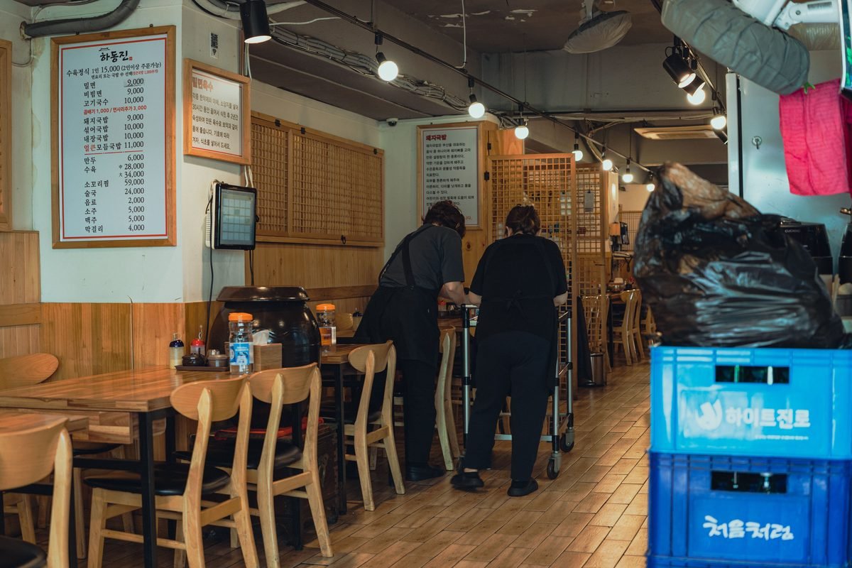 Interior of a traditional Korean restaurant with wooden furniture and staff working.