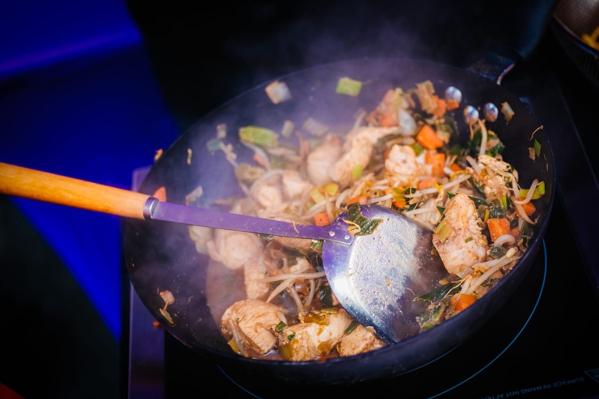 Sizzling chicken stir fry with vegetables cooked in a wok.