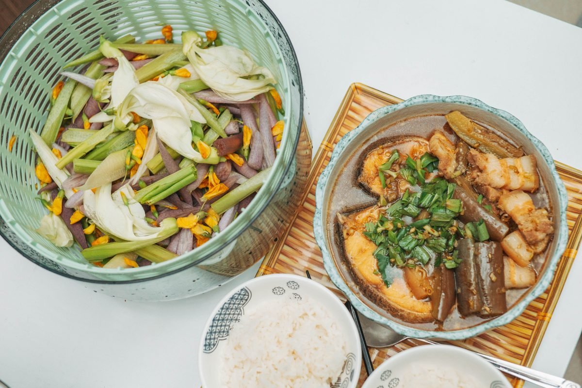 Table spread featuring a bowl of cooked fish and seasoned vegetables
