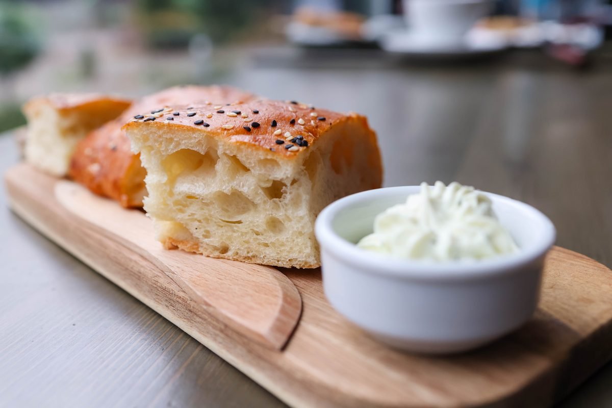 Slice of focaccia bread served with cream cheese.
