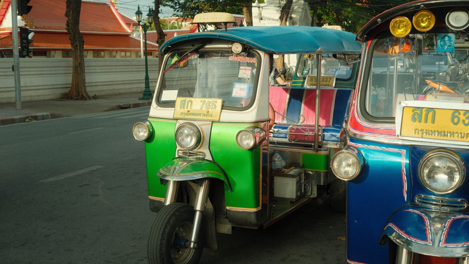 Colorful auto rickshaws line a bustling street in Bangkok.