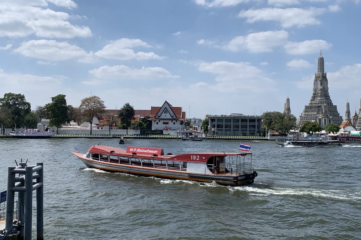 Express boat on Chao Phraya River with Bangkok skyline.