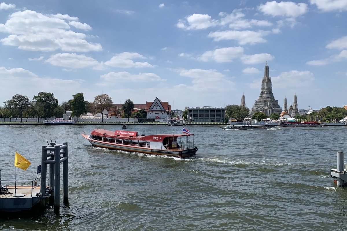 Classic red express boat cruising along the Chao Phraya River in Bangkok.