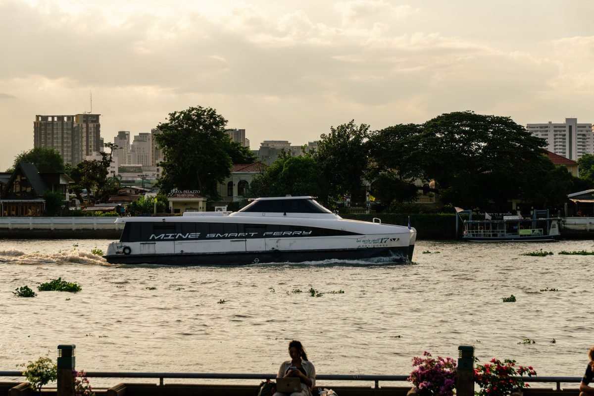 A sleek eco-friendly ferry navigates the Chao Phraya River in Bangkok.