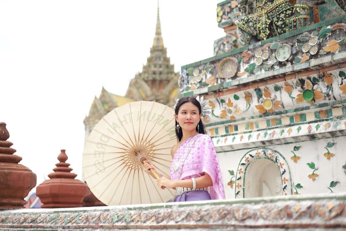 Woman in traditional Thai dress with parasol at Wat Arun.