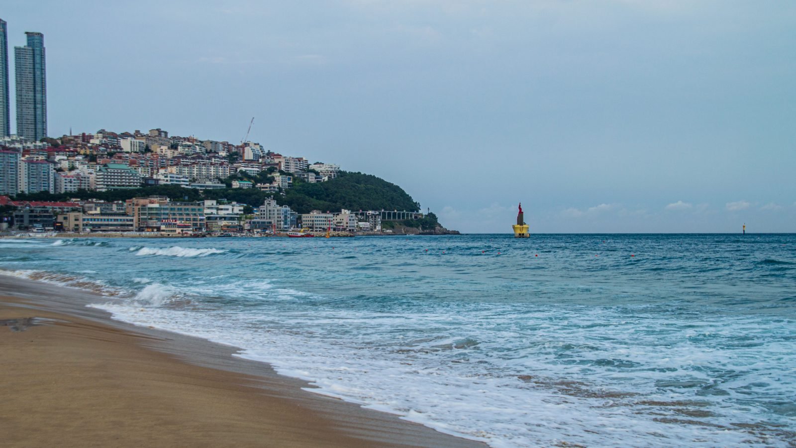 Wide shot of Haeundae beach and coastline with city buildings