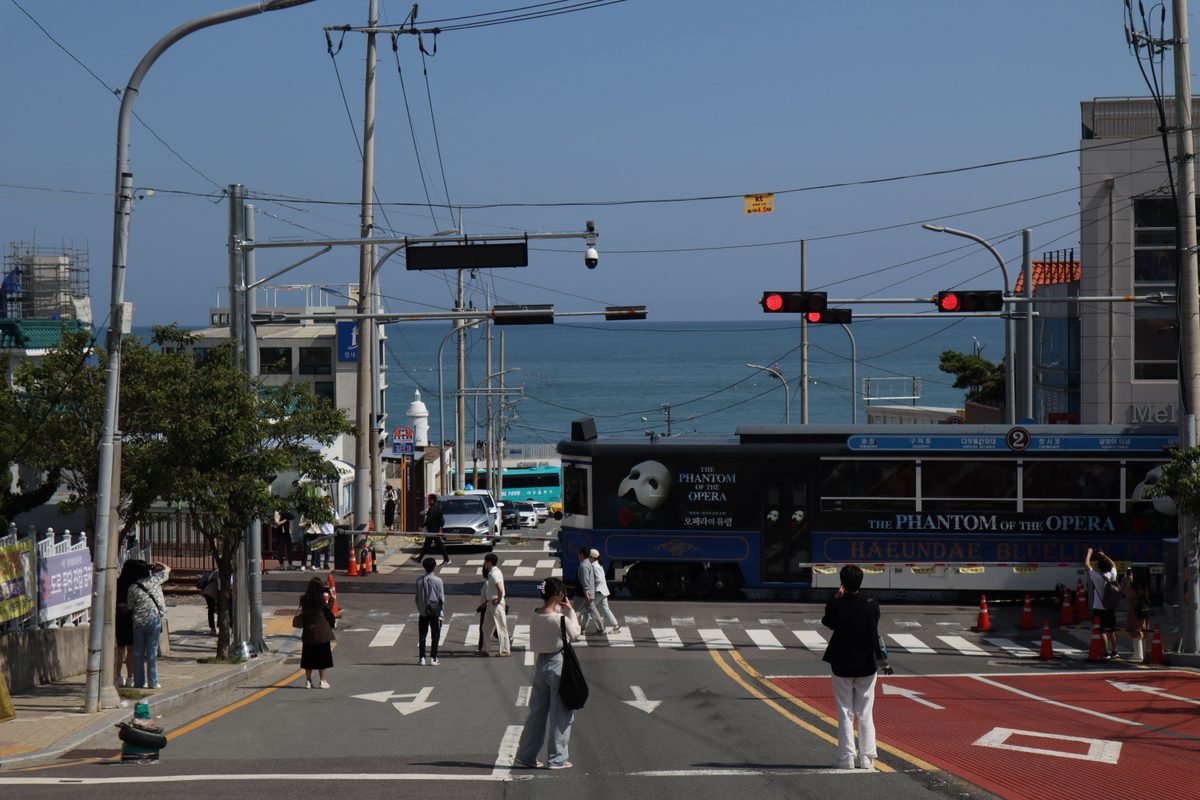 Blue tourist beach train crossing a street near the ocean