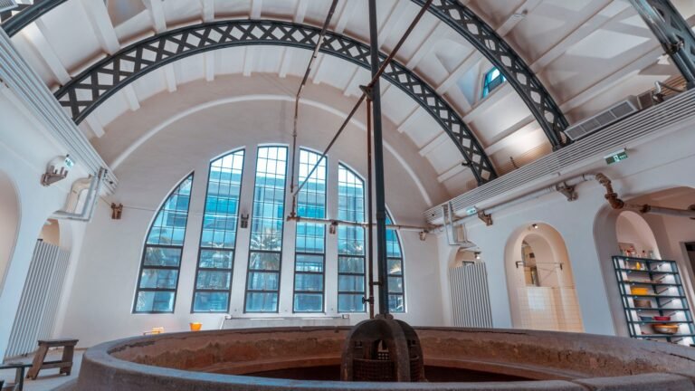 Expansive industrial bathhouse interior featuring an arched roof and a large central pool basin.