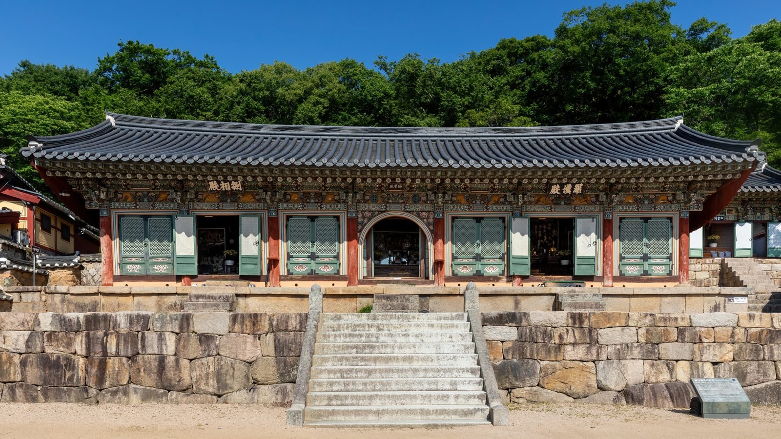 Front exterior view of Beomeosa Buddhist temple with stairs under a sunny blue sky in Busan