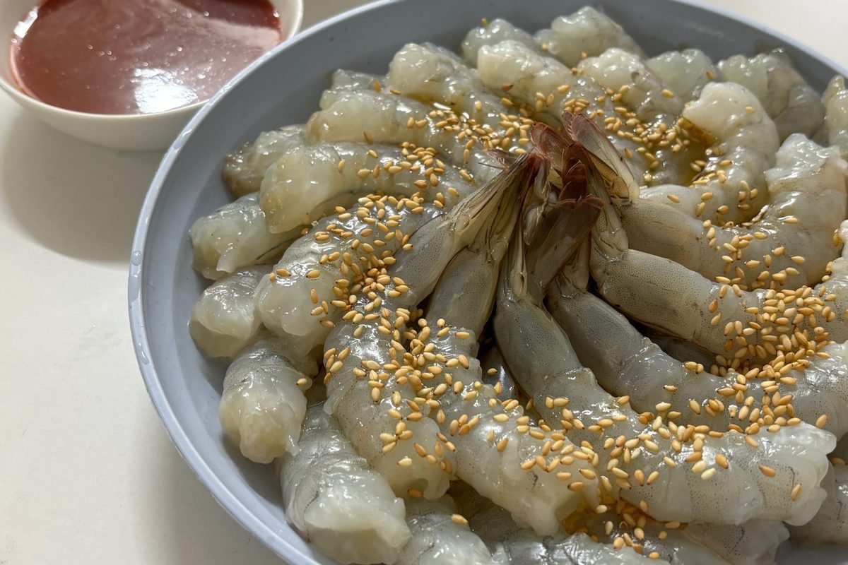 Plate of raw shrimp with sesame seeds and a spicy dipping sauce