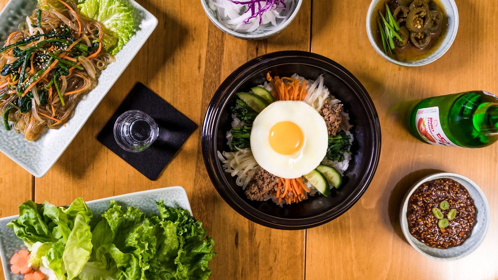 Assortment of Korean dishes including bibimbap in a flatlay