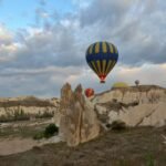 Colorful hot air balloons floating over rocky valleys in Cappadocia at sunrise