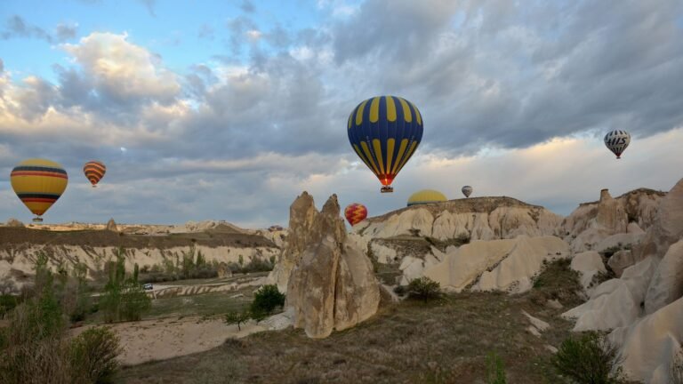 Colorful hot air balloons floating over rocky valleys in Cappadocia at sunrise