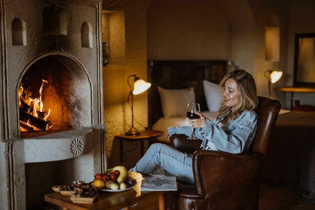 Woman enjoying wine by a stone fireplace in a luxury cave hotel in Ürgüp