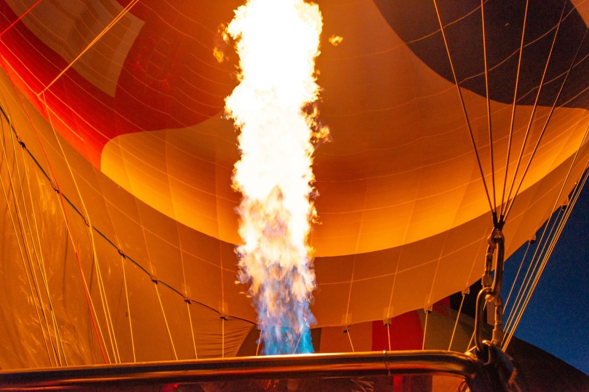 Vibrant flame from a burner lighting up the inside of a hot air balloon