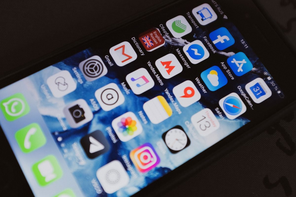 Smartphone displaying various application icons on its screen indoors