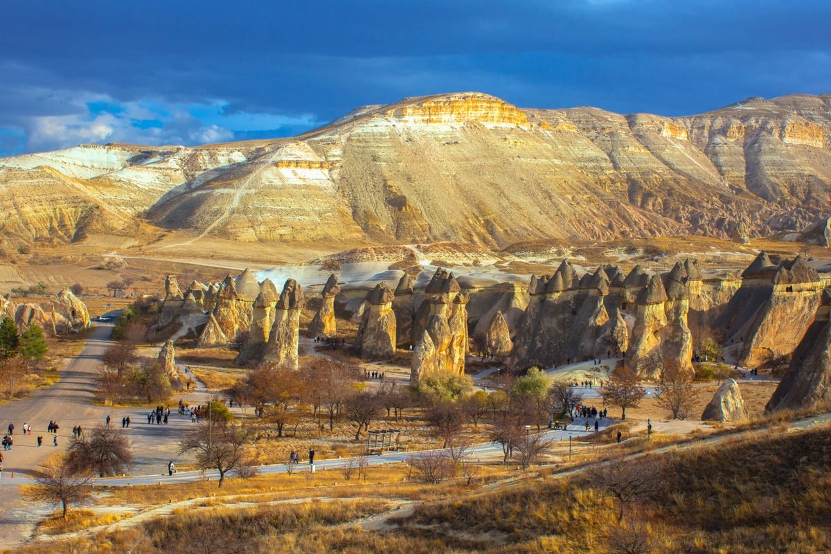 Hot air balloons flying over town rooftops and rock formations in Cappadocia