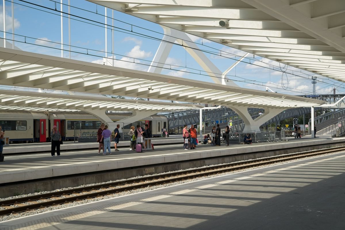Modern train station platform under a sleek canopy with waiting passengers