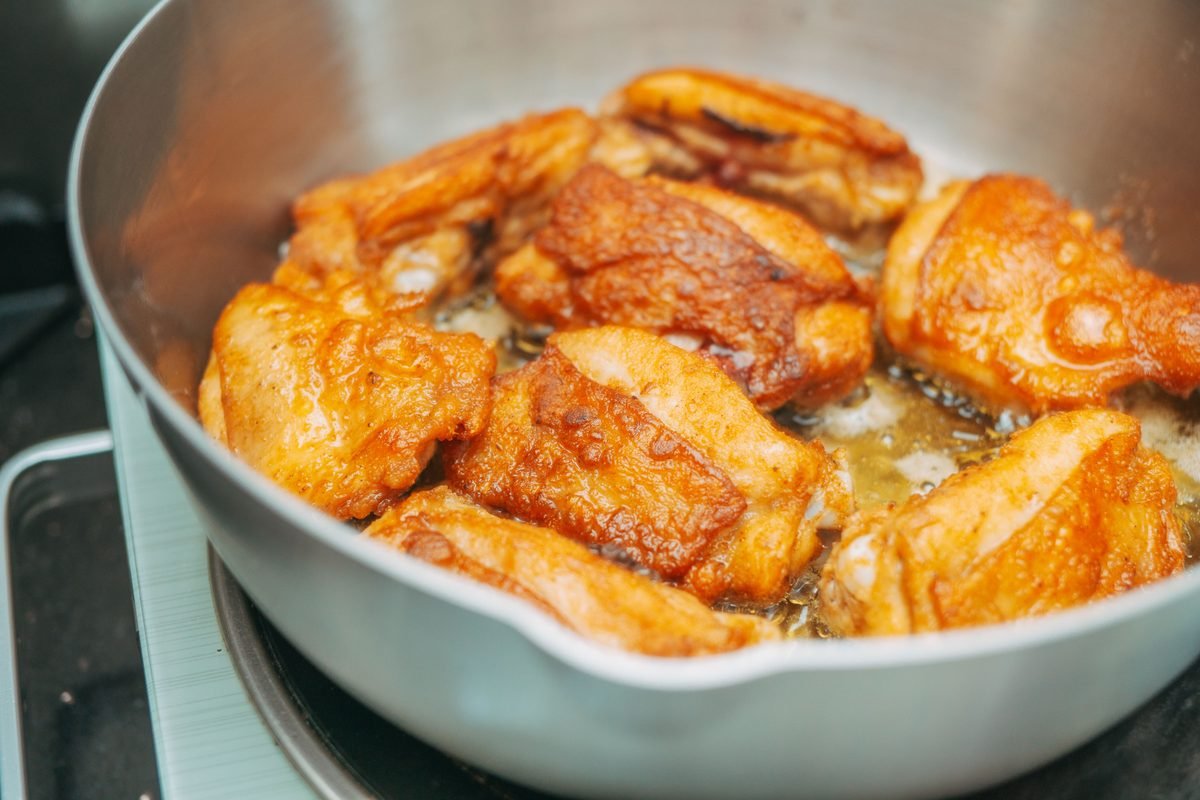 Crispy chicken thighs sizzling in a hot pan