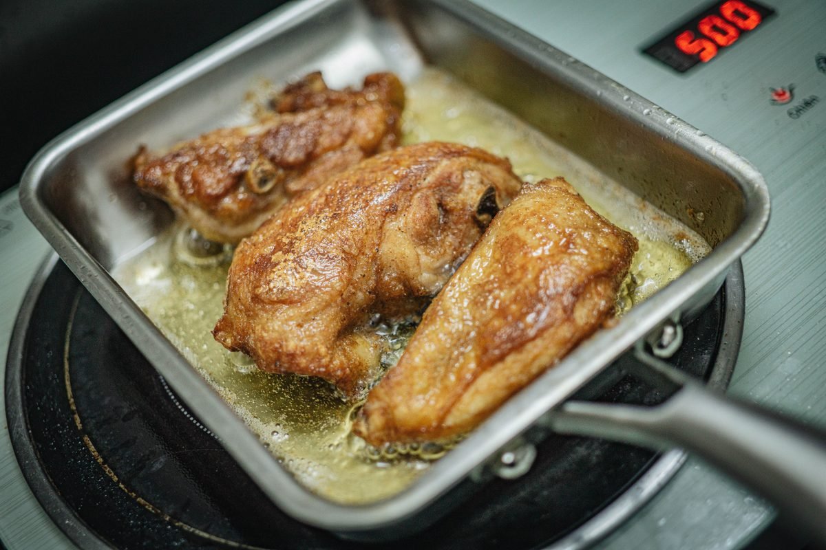 Golden brown chicken frying in a pan on a stovetop