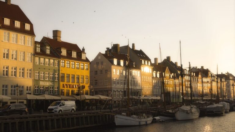 Morning sunlight on the colorful historic buildings and moored boats along Nyhavn canal in Copenhagen
