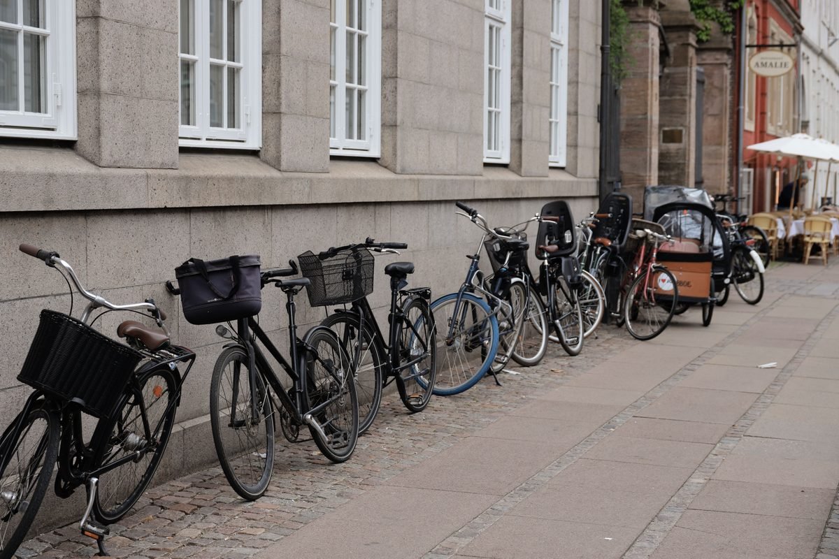 A row of urban bicycles parked securely on a Copenhagen sidewalk