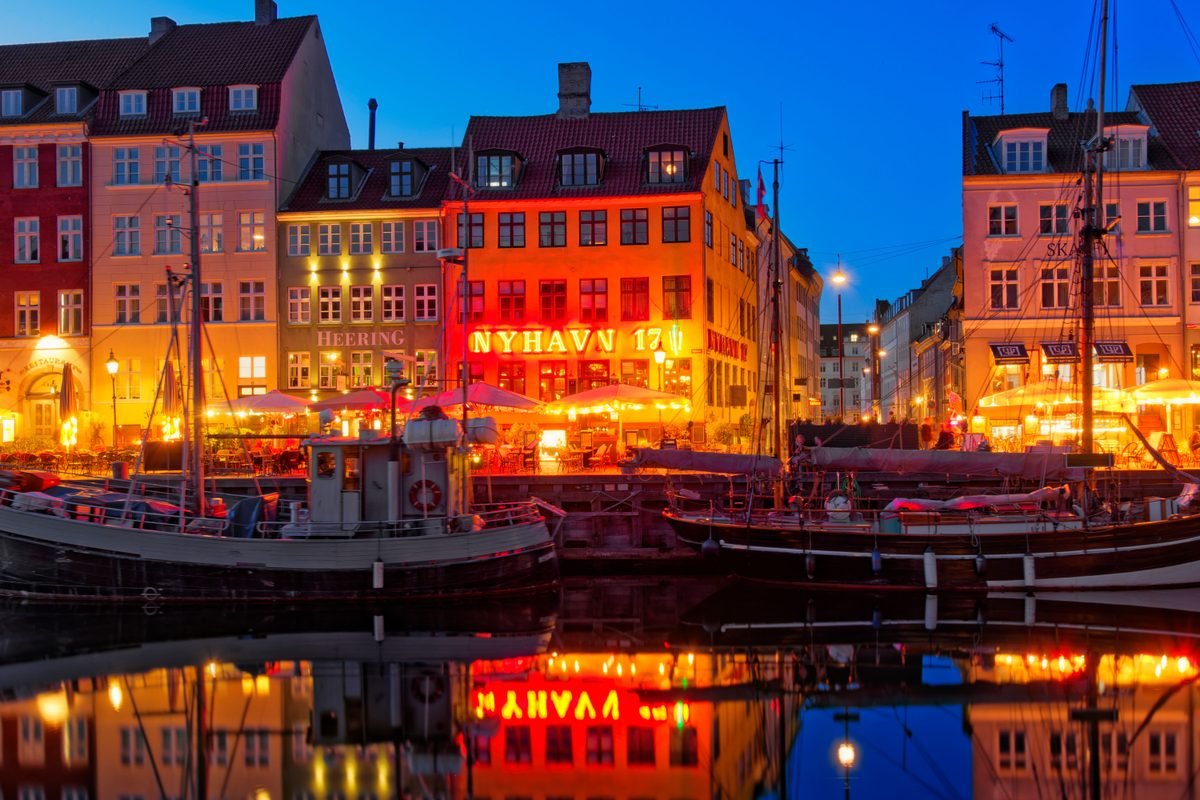 Colorful historic facades illuminated at dusk reflecting in the canal water