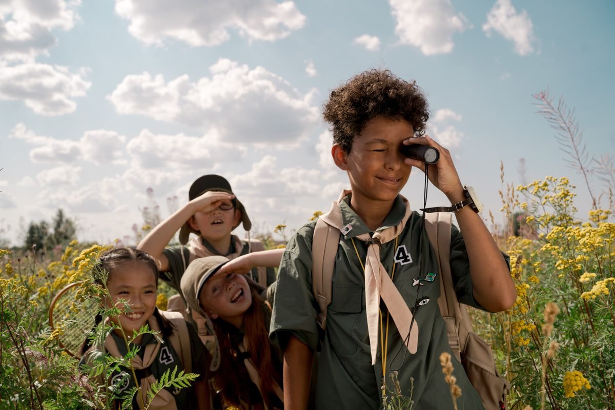 Children in scout uniforms using a spotting scope