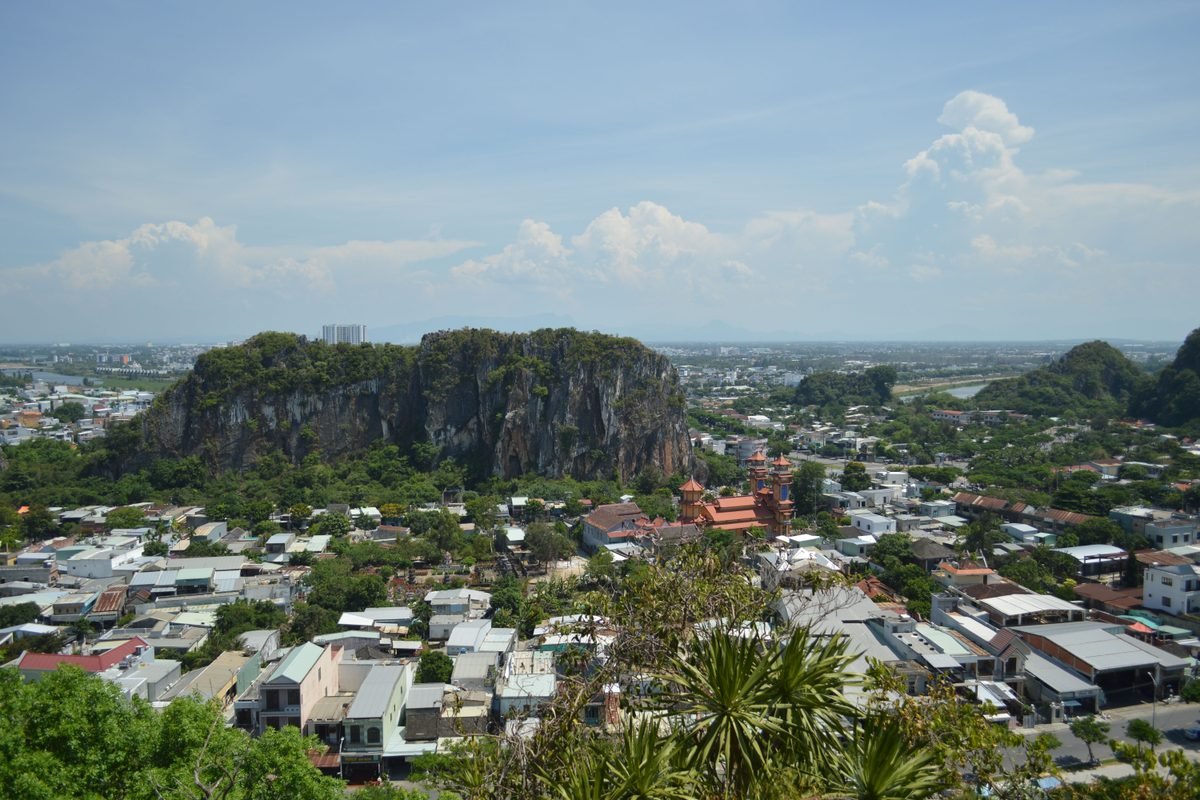 Aerial view showcasing city with prominent rocky hill and lush landscape