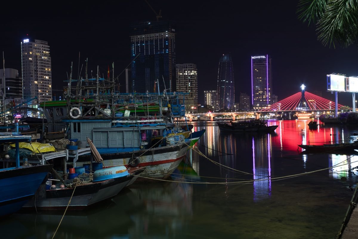 Illuminated cityscape of Da Nang at night featuring boats and bridge
