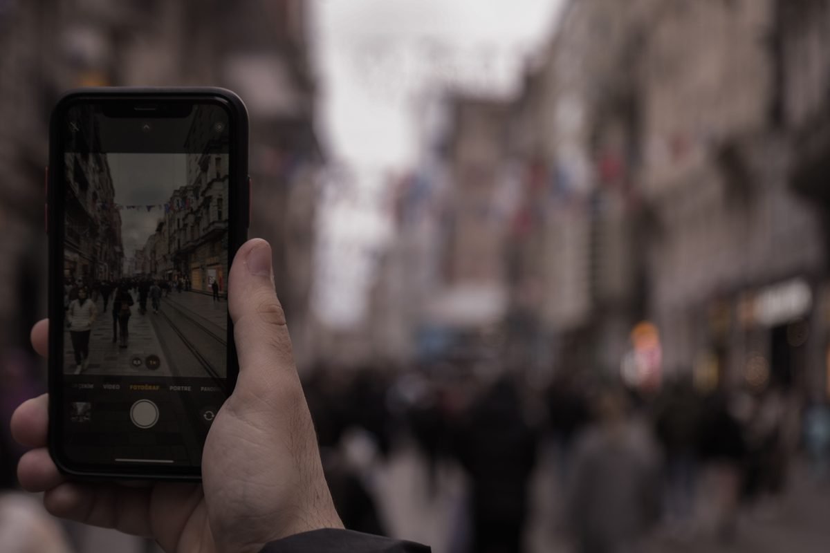 Hand capturing bustling city street scene with a smartphone