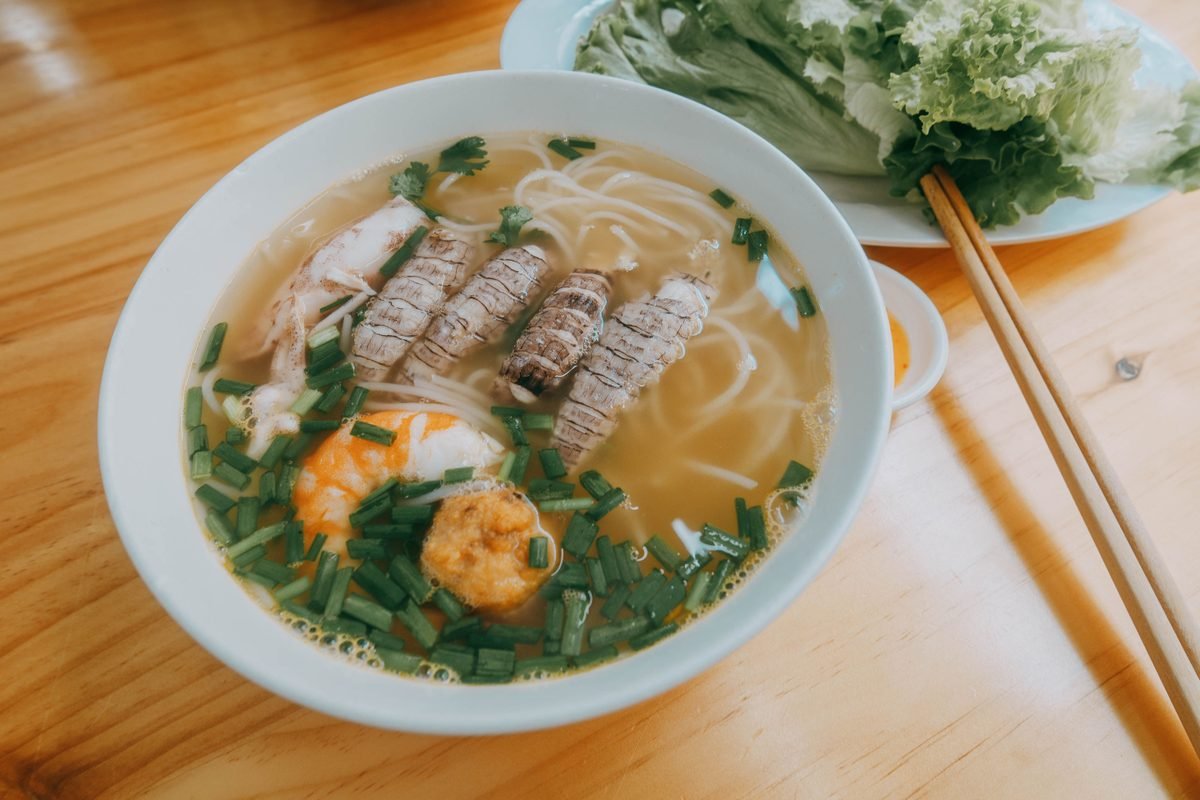 A bowl of seafood noodle soup with fresh herbs.
