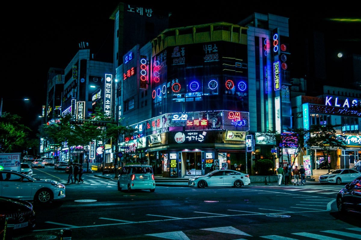Illuminated city street in Gwangju at night with neon lights and traffic.