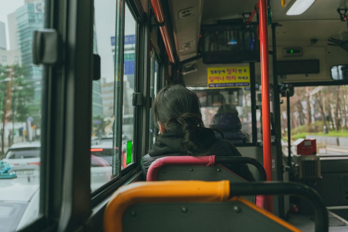 View from inside a crowded city bus looking out at urban traffic.