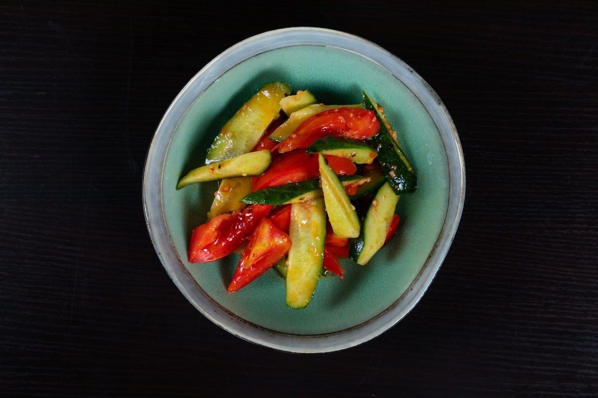 A colorful salad with sliced cucumbers and peppers in a ceramic bowl.