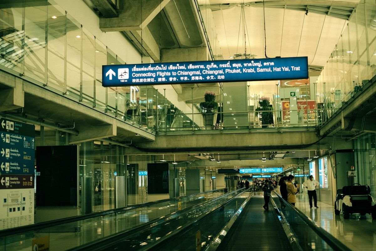Airport interior with moving walkway and overhead connecting flight signs