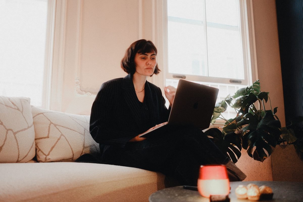 Woman in suit using laptop on a sofa indoors