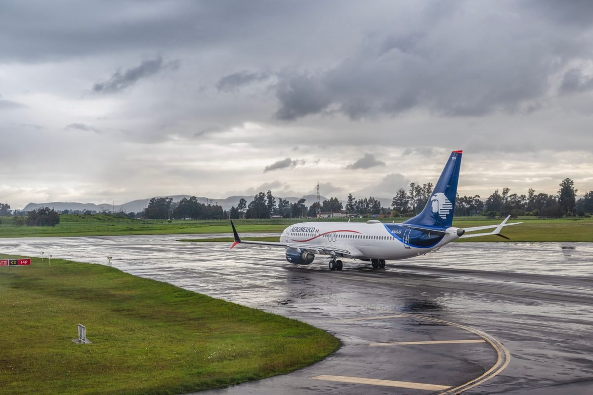 Commercial airplane taxiing on a wet runway under stormy skies