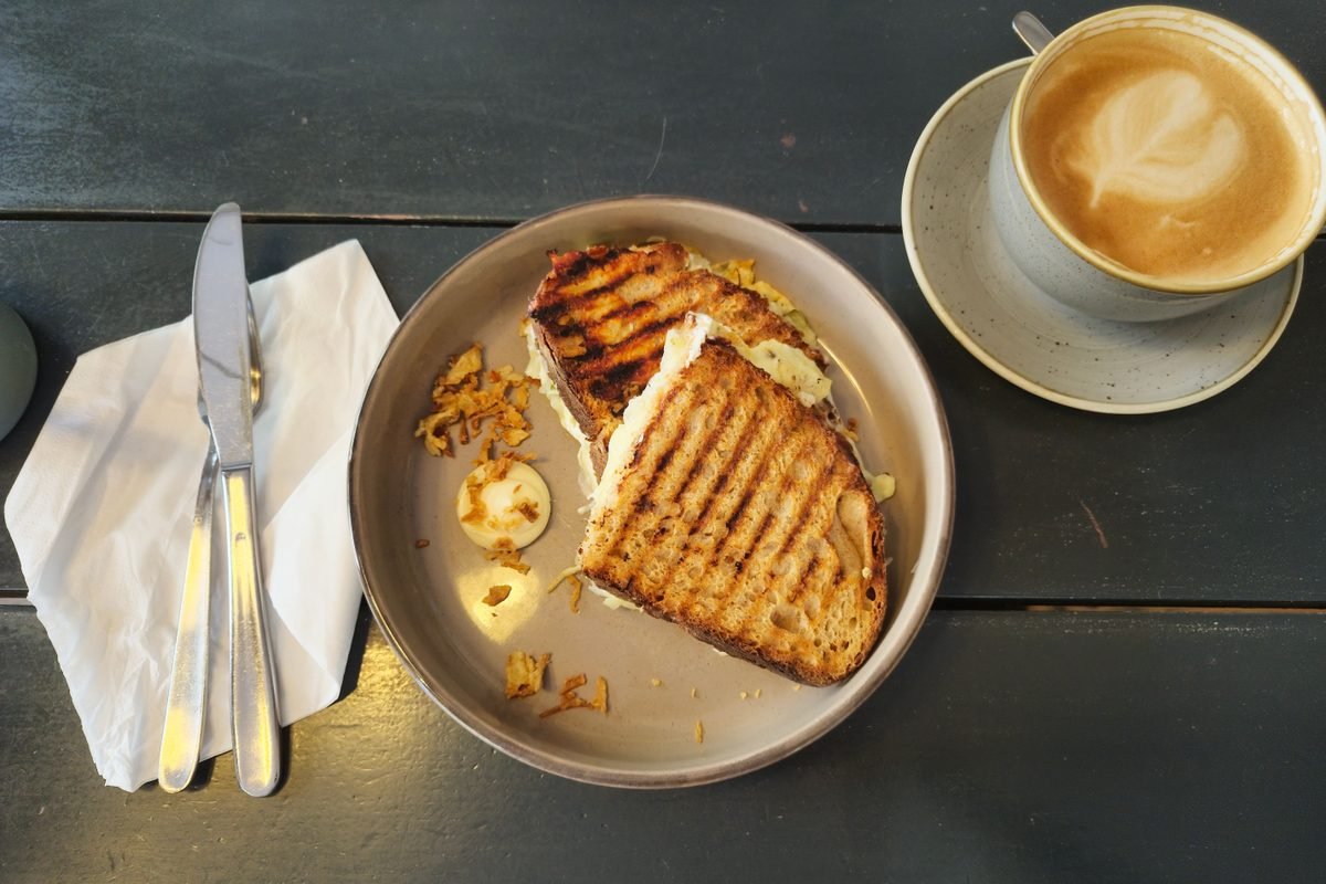 Grilled sandwich and cappuccino on a dark cafe table