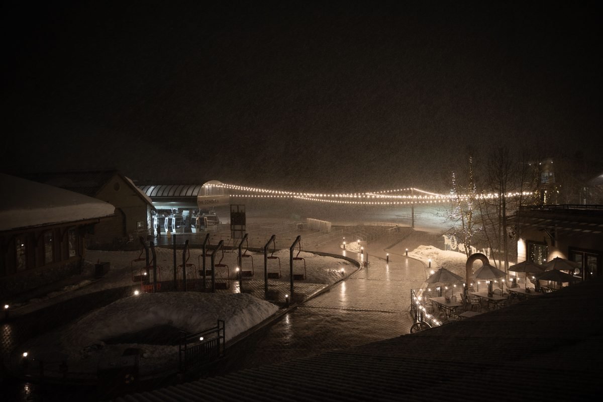 Illuminated ski resort lodge and lifts during evening snow
