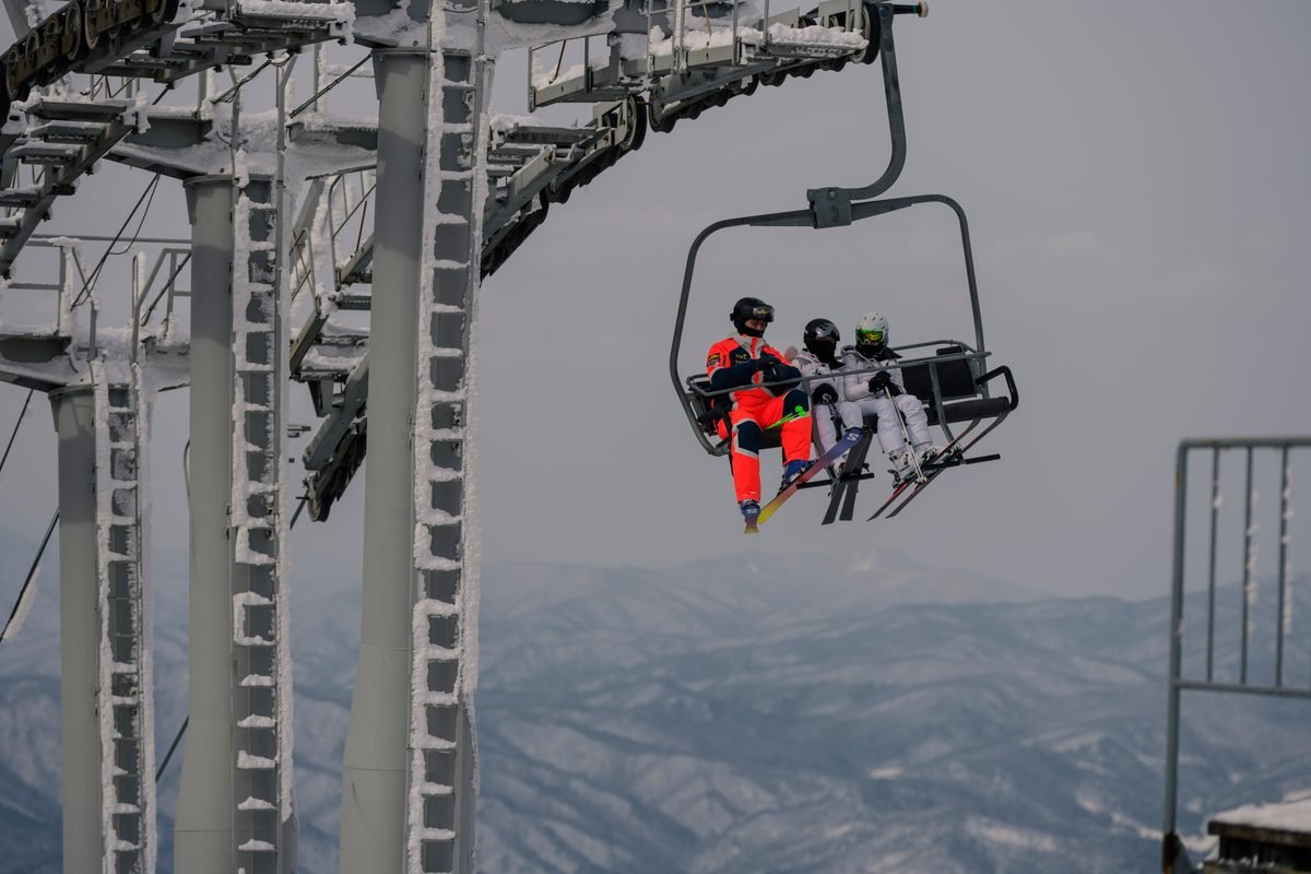 Skiers riding a chairlift over snowy mountain ridges
