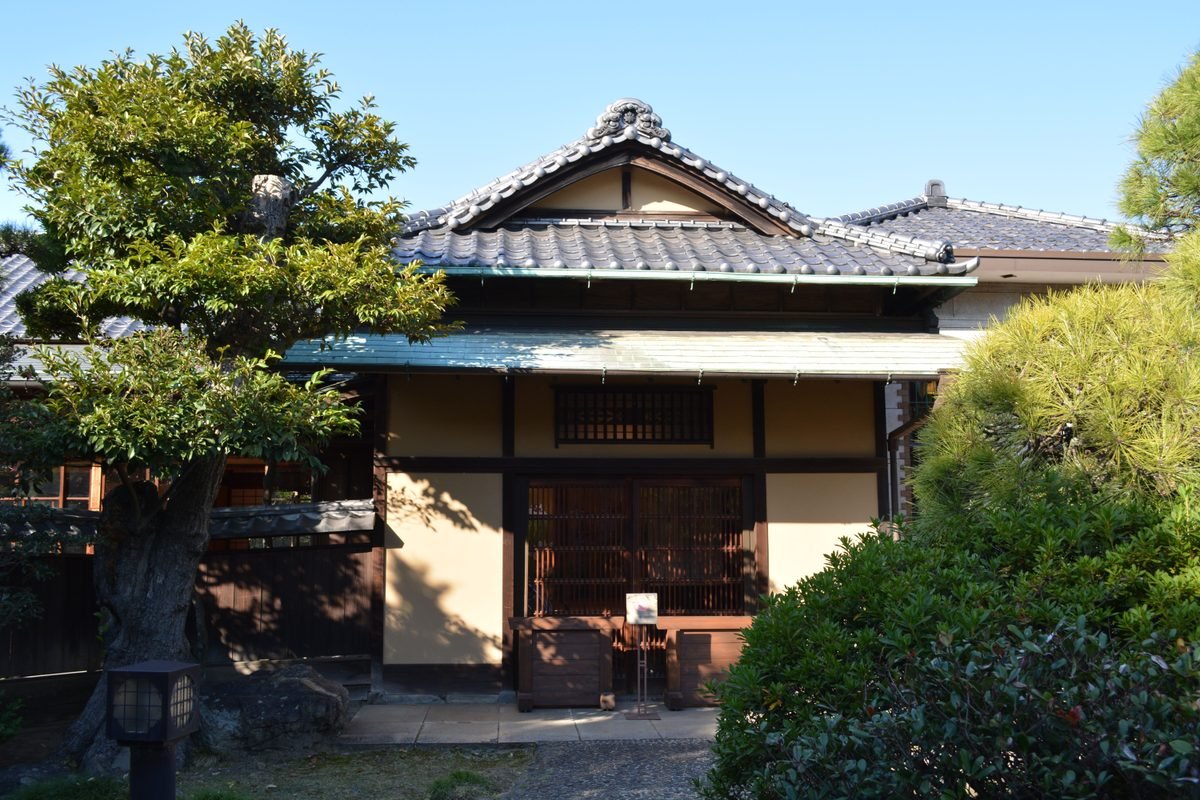 Traditional Japanese style wooden house with tiled roof and green foliage